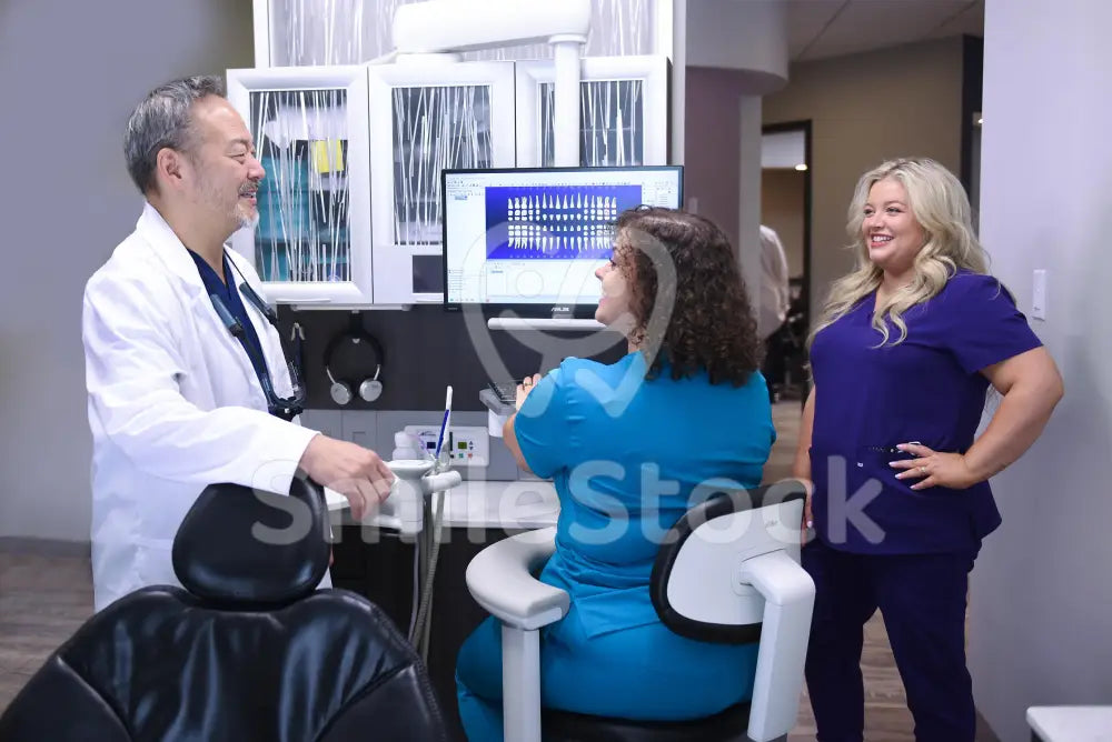 Three Dental Staff Members Reviewing Patient Charts - Dental Team Images